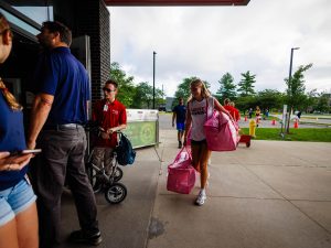 A young woman carries bags into a university residence building.