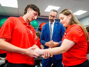 A student assesses another student's wrist while a third person looks on.