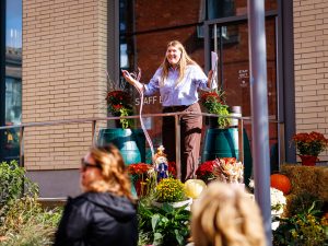 A woman speaks to an audience outside a building.