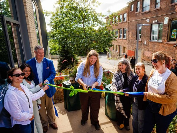 A group of people cut a green ribbon at an opening ceremony for a rain garden.