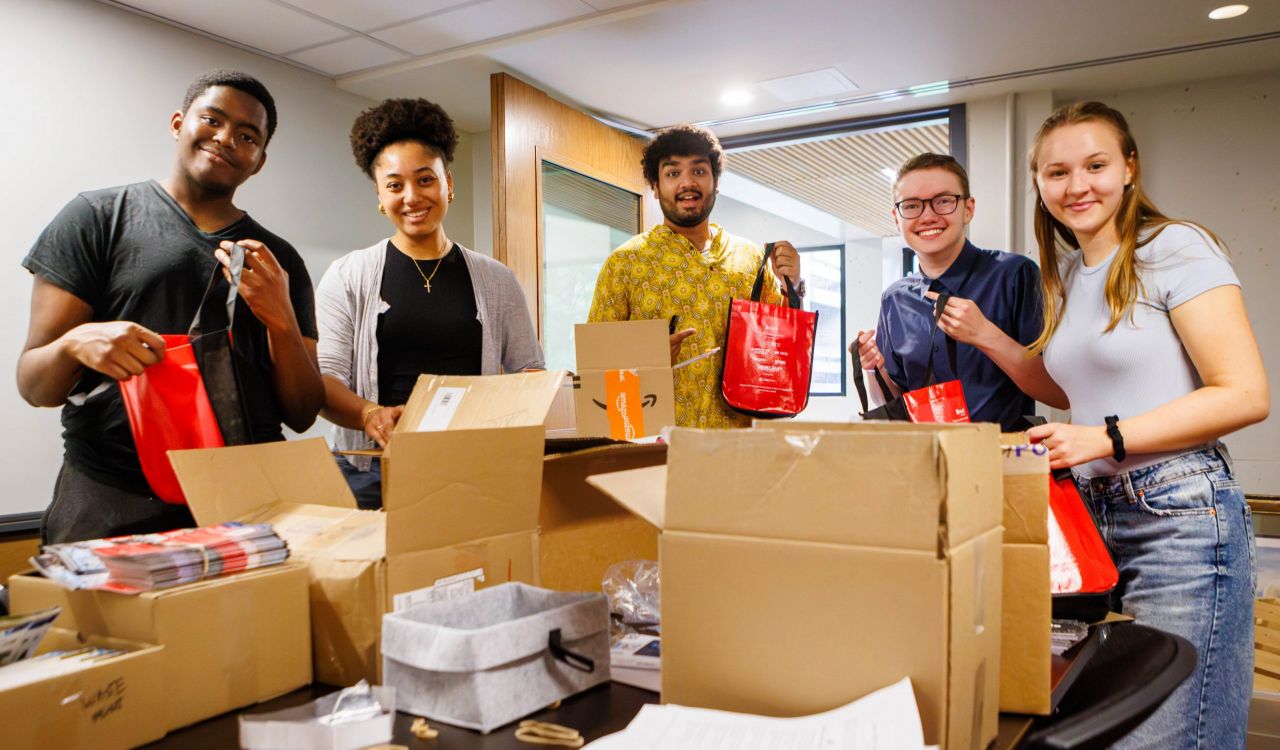 Five Brock University students prepare Welcome Wagon packages and materials for incoming students.