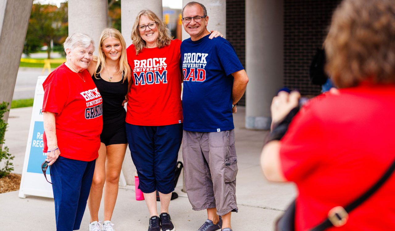 Four people stand beside each other posing for a photo outside a building.