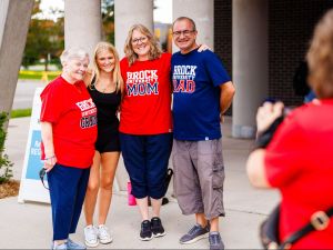Four people stand beside each other posing for a photo outside a building.
