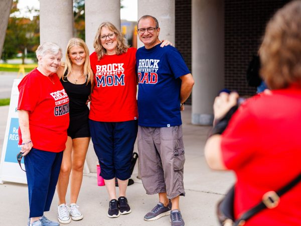 Four people stand beside each other posing for a photo outside a building.