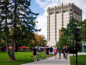 Brock University's Schmon Tower with people walking around courtyard below it.