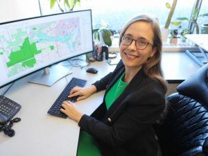 Samantha Hajna sits at her desk, with a large screen displaying a map and her hands on a keyboard.