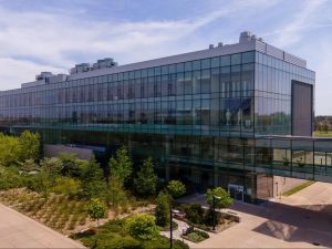 A glass building surrounded by gardens on a sunny day.