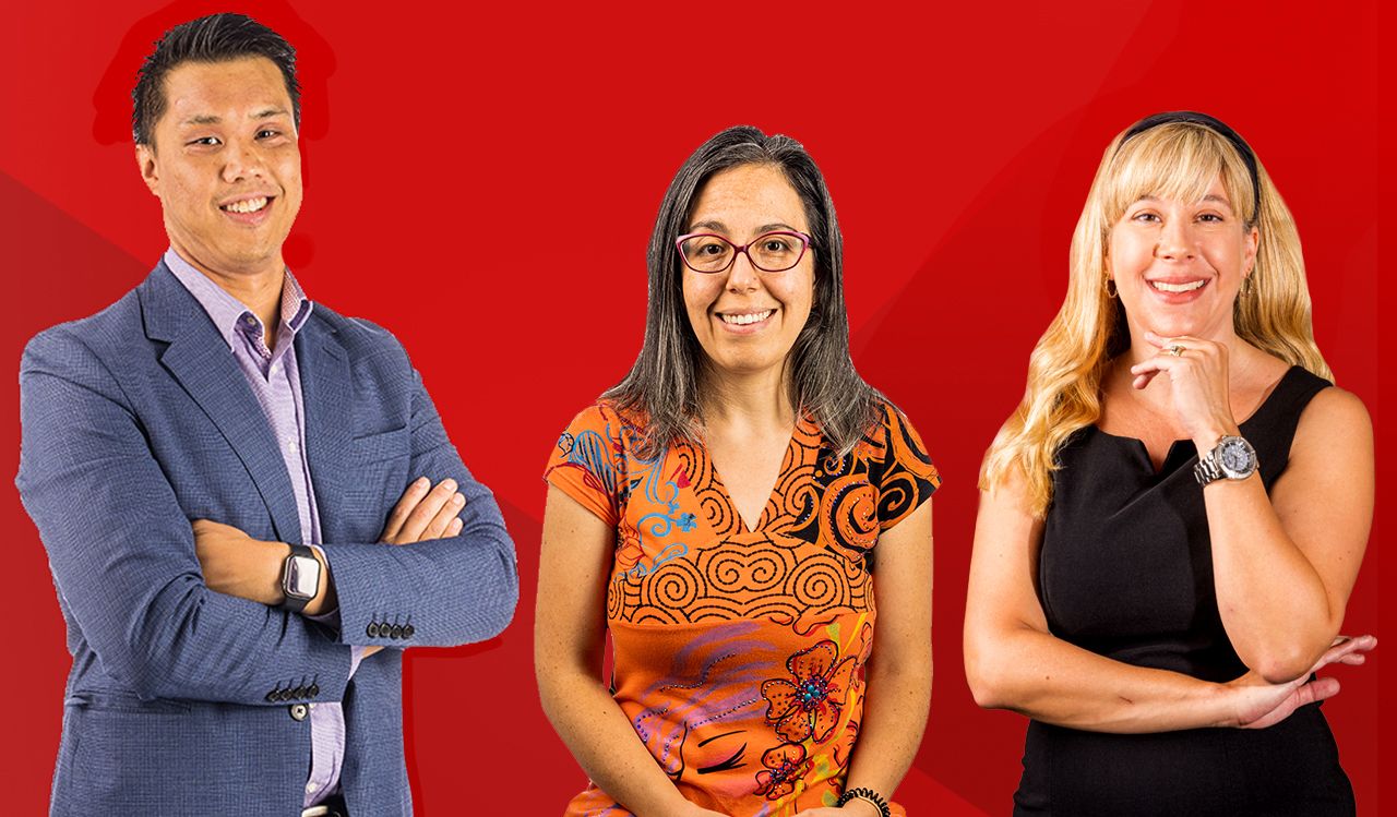 Three people stand together against a red backdrop.