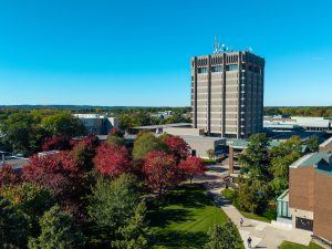 A large concrete tower stands at the heart of a university campus with fall foliage and colourful leaves lining a variety of buildings.