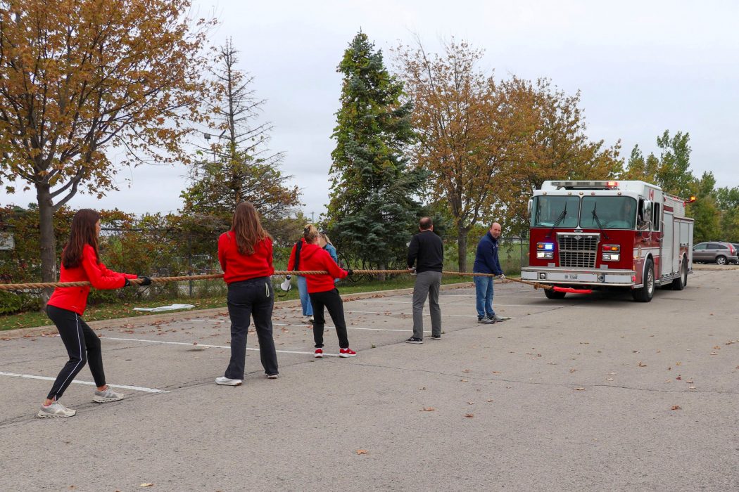 A group of people pull a fire truck.