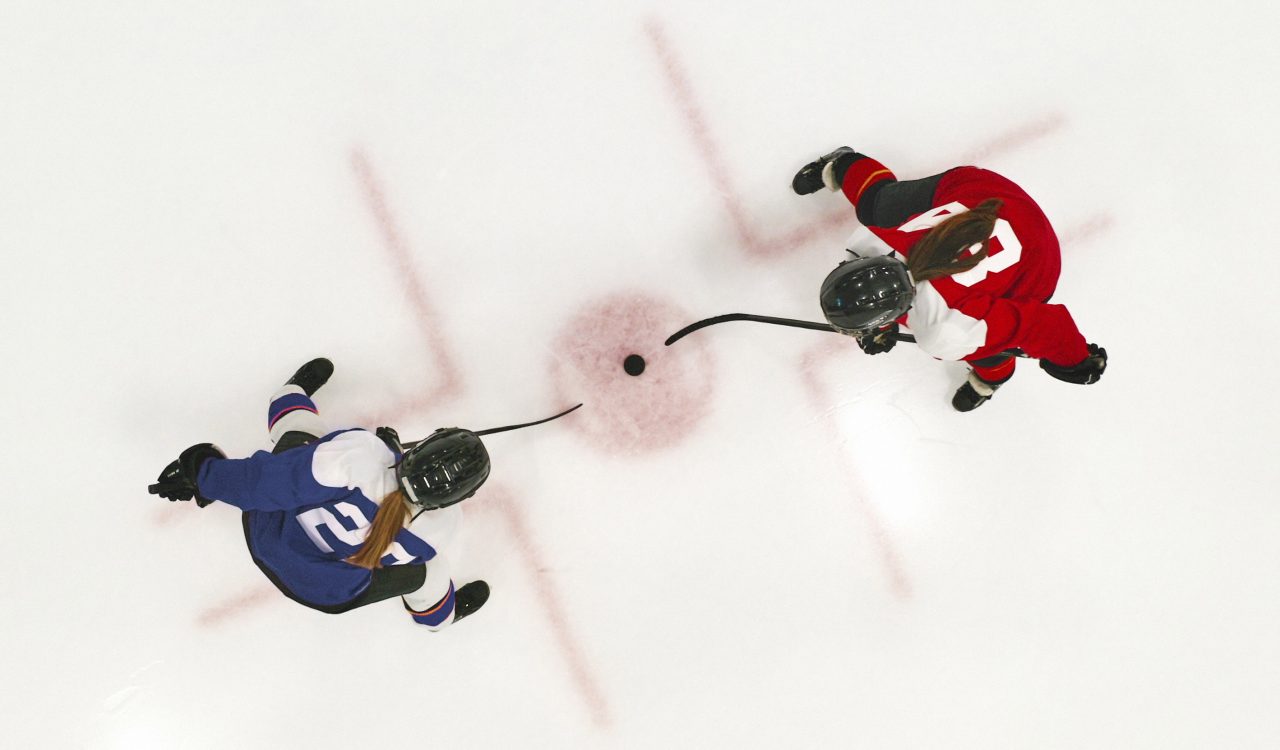 Two women play ice hockey.