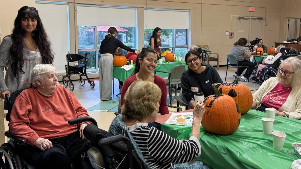 A group of residents at a seniors home do crafts with volunteers from a university.