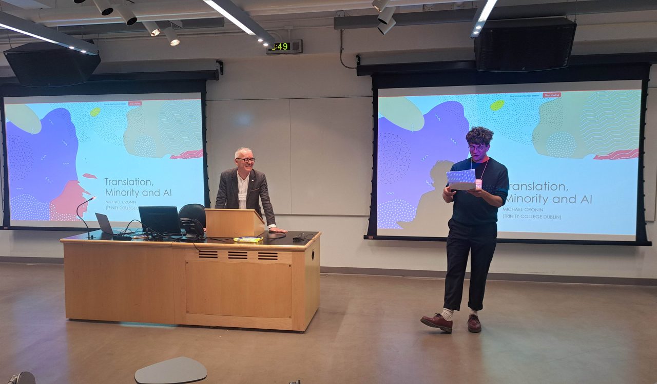 Nicholas Hauck and Michael Cronin stand at the front of a lecture hall at Brock University addressing a room.