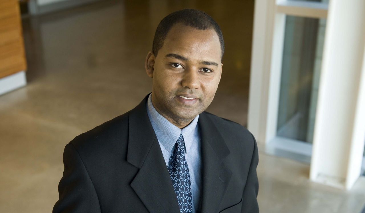 Professor of Information Systems Anteneh Ayanso stands in a hallway, looking up at the camera.