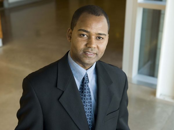 Professor of Information Systems Anteneh Ayanso stands in a hallway, looking up at the camera.