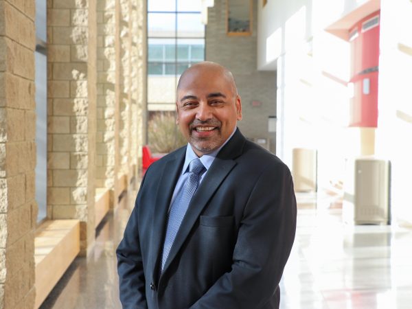 Rahul Kumar stands in a brightly lit hallway at Brock University.