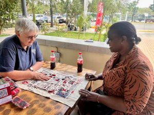 Two women look at an illustrated cloth on a table on a patio.
