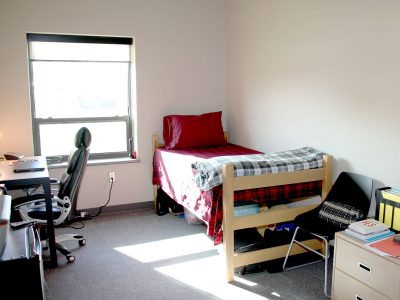 Individual furnished room with bed, chair, desk, mini fridge and dresser