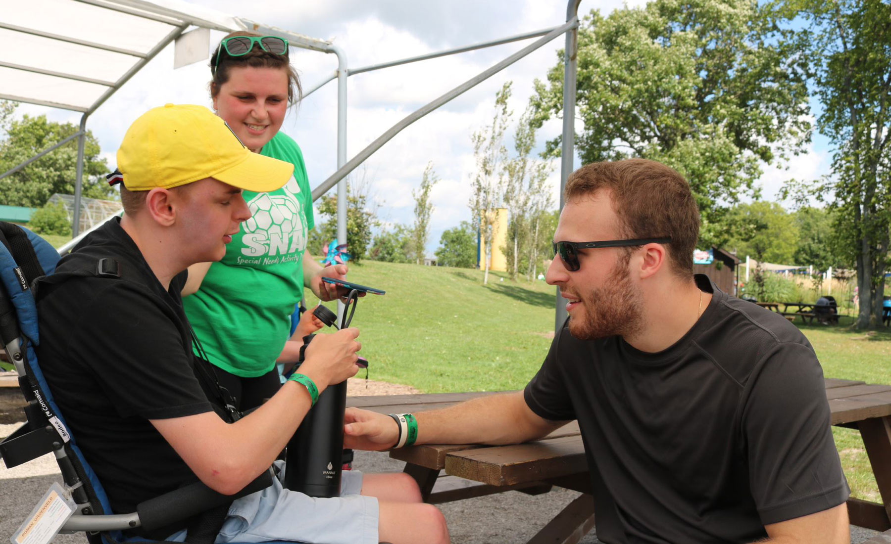 Two student volunteers and a participant sitting at a picnic table.