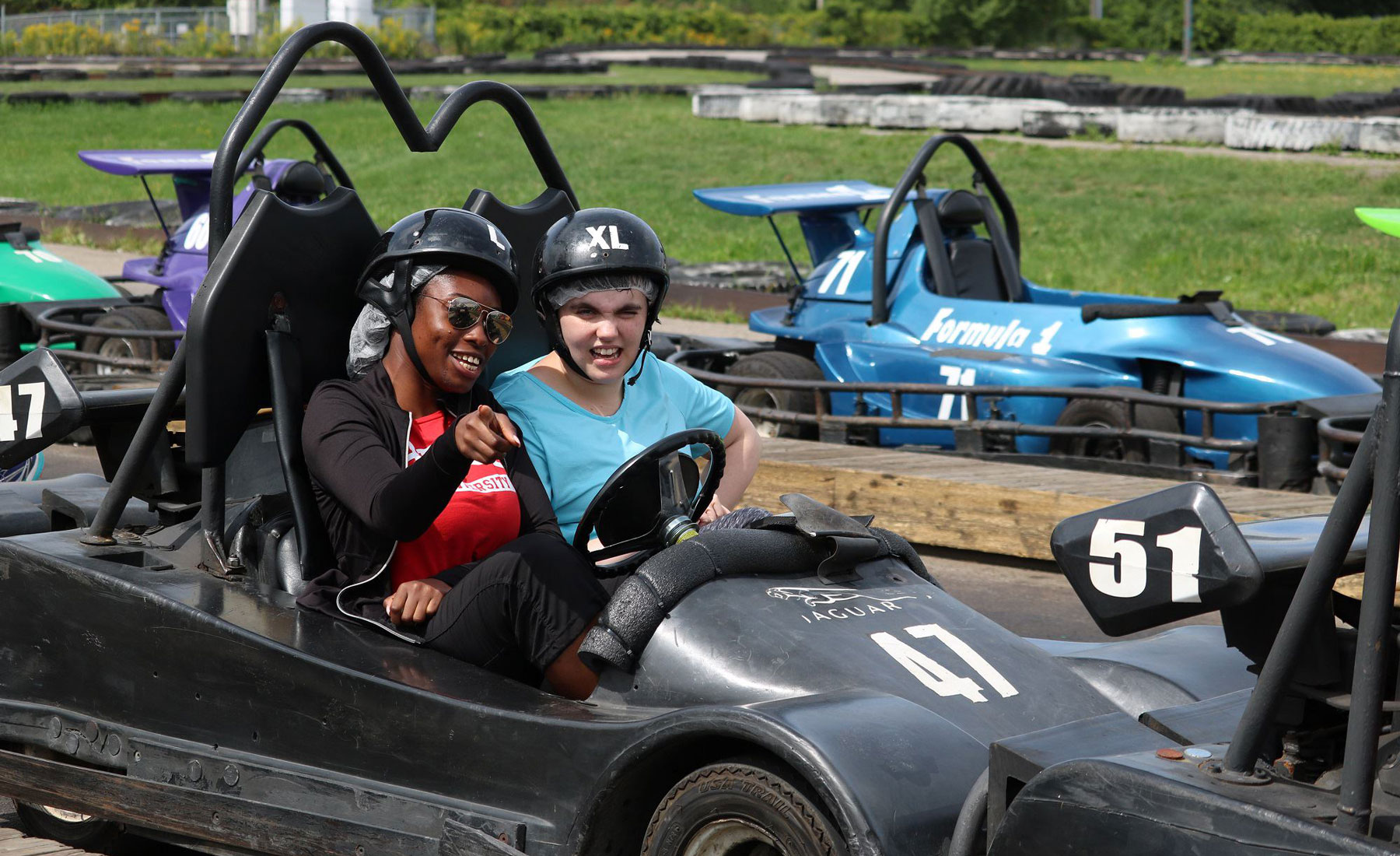 A participant and camp counsellor riding in a go-cart.