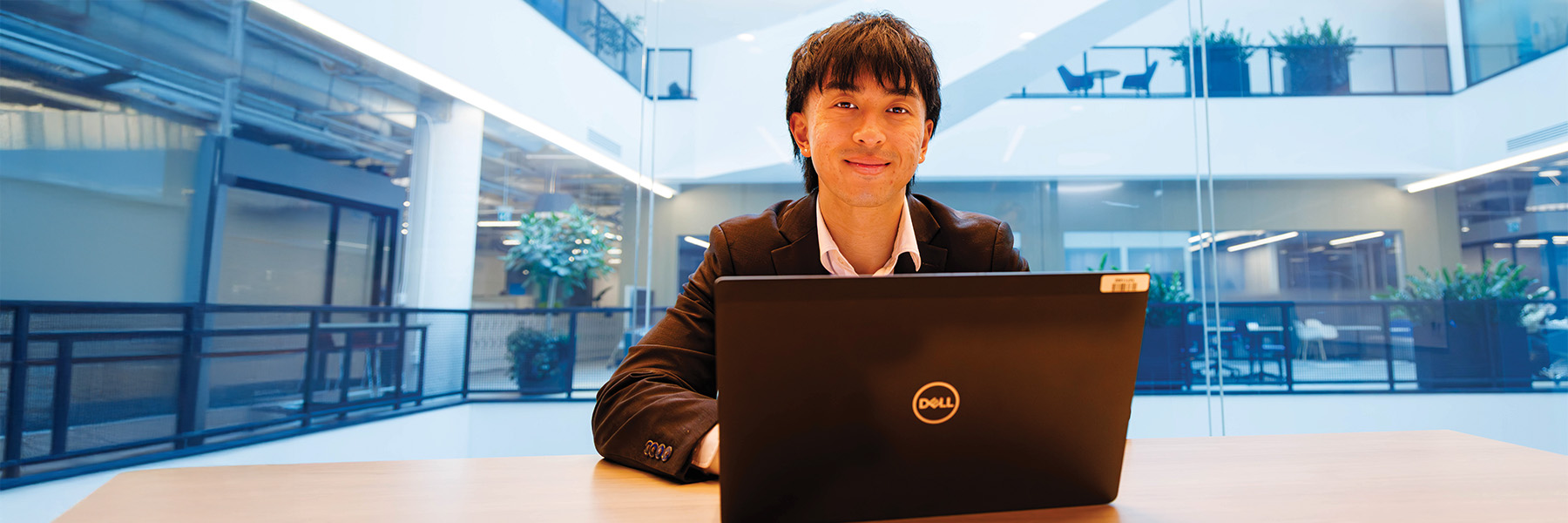 A Brock co-op student, sitting at a desk and using a laptop in an office setting.