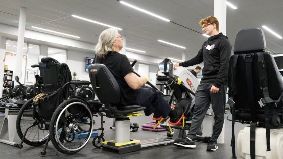 Brock University's Fit Link Instructor talking with elderly man on a stationary bike