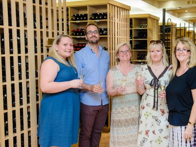 5 people inside a wine room smiling and holding a glass of wine