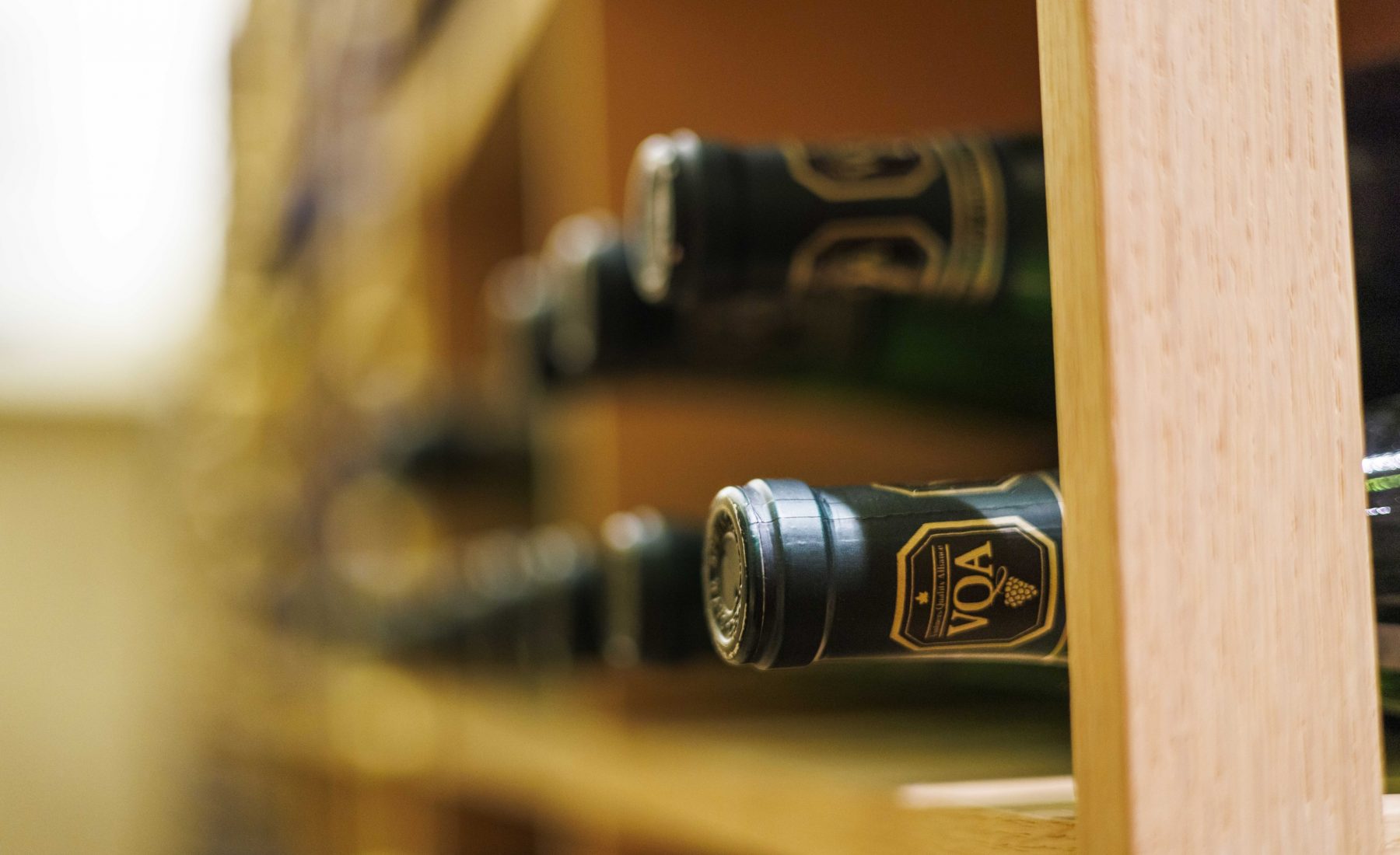 Image of wine bottles with VQA seal laying on their side in a wine cellar shelf 