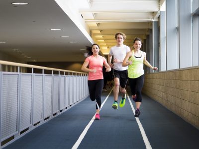 3 students running on the 200m indoor track is suspended above the Ian Beddis gymnasium