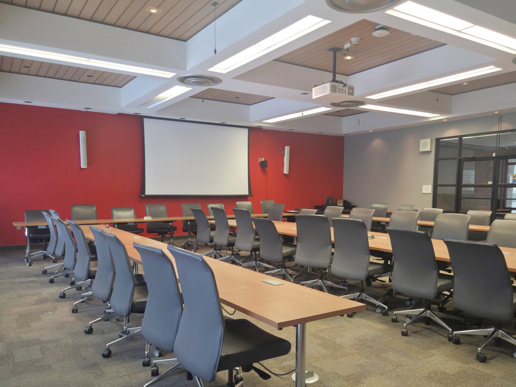 Sankey Chamber Boardroom with U-shaped meeting tables, seating for multiple attendees, presentation screen, and contemporary conference room amenities