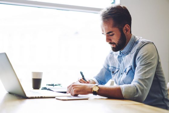 Man at desk in front of window with laptop