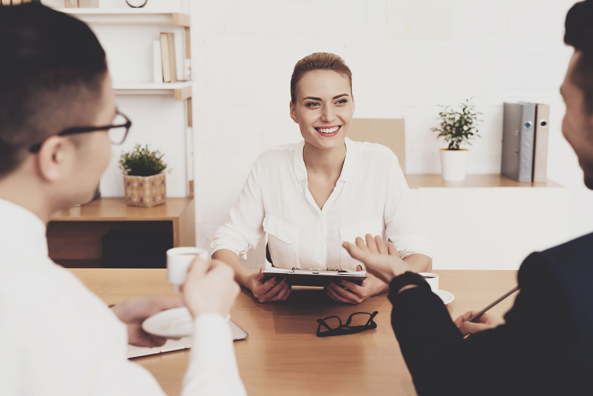 Two men are interviewing a woman sitting at table