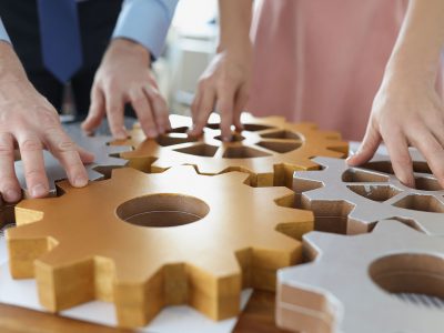 Close-up of businesspeople put wooden gears on workplace together, work in team. Teamwork, cooperation, successful development, game, erudition concept