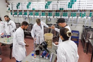 winemaking lab with class of students in white labcoats making wine