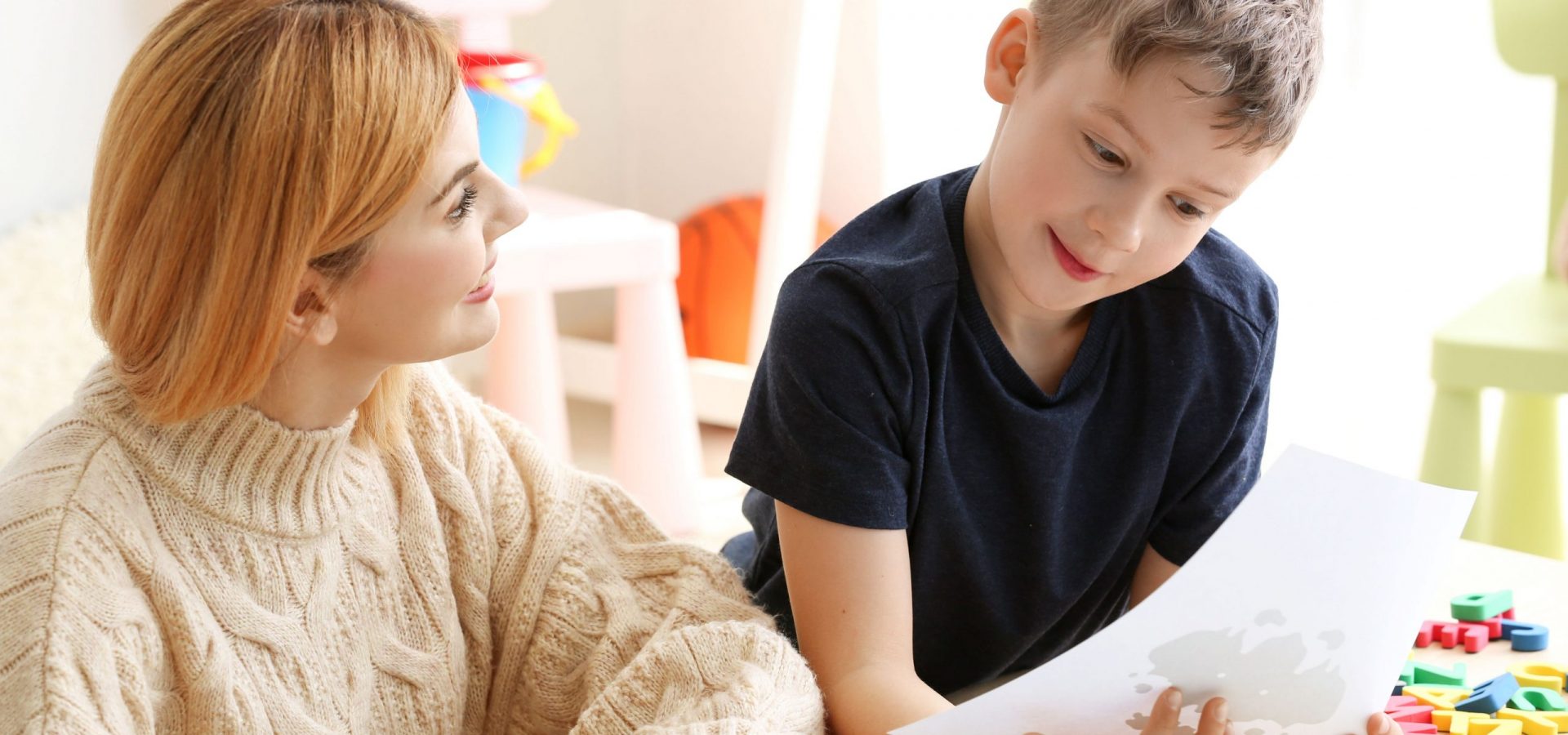 young boy looking at image on paper guided by adult