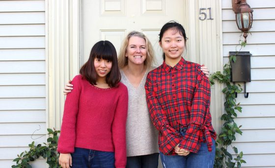 three people standing in front of a doorway to a house