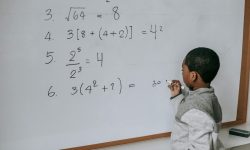 A young boy doing math on a classroom whiteboard