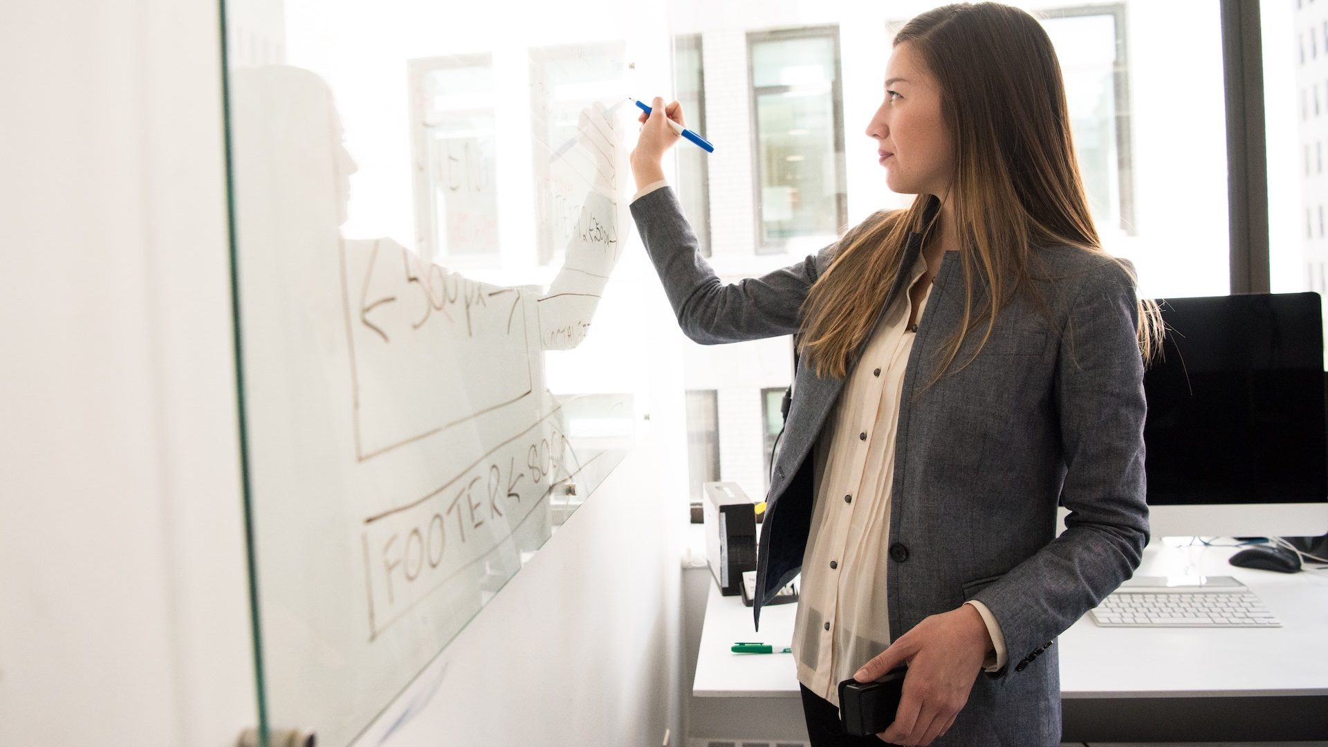 person writing something on whiteboard in office