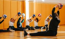 Gym teacher and students doing stretching exercises