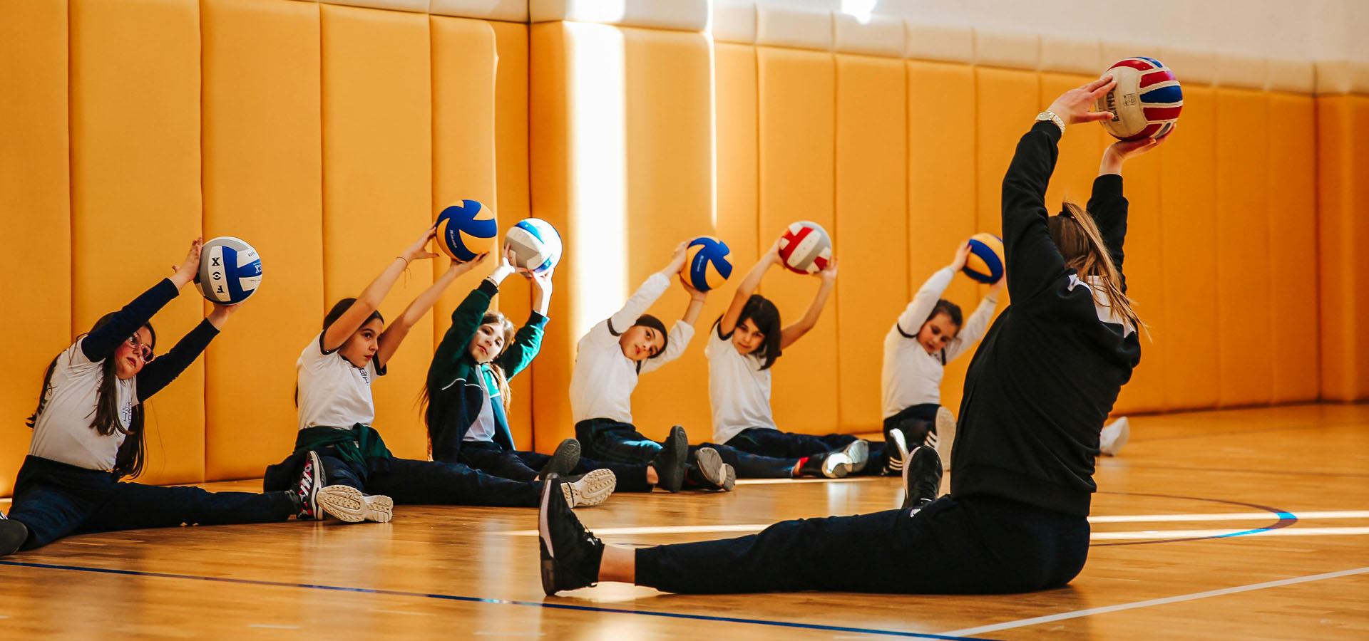 Gym teacher and students doing stretching exercises