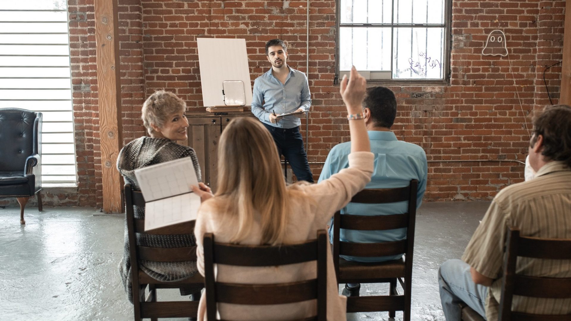 group of people listening to presentation and one raising their hand