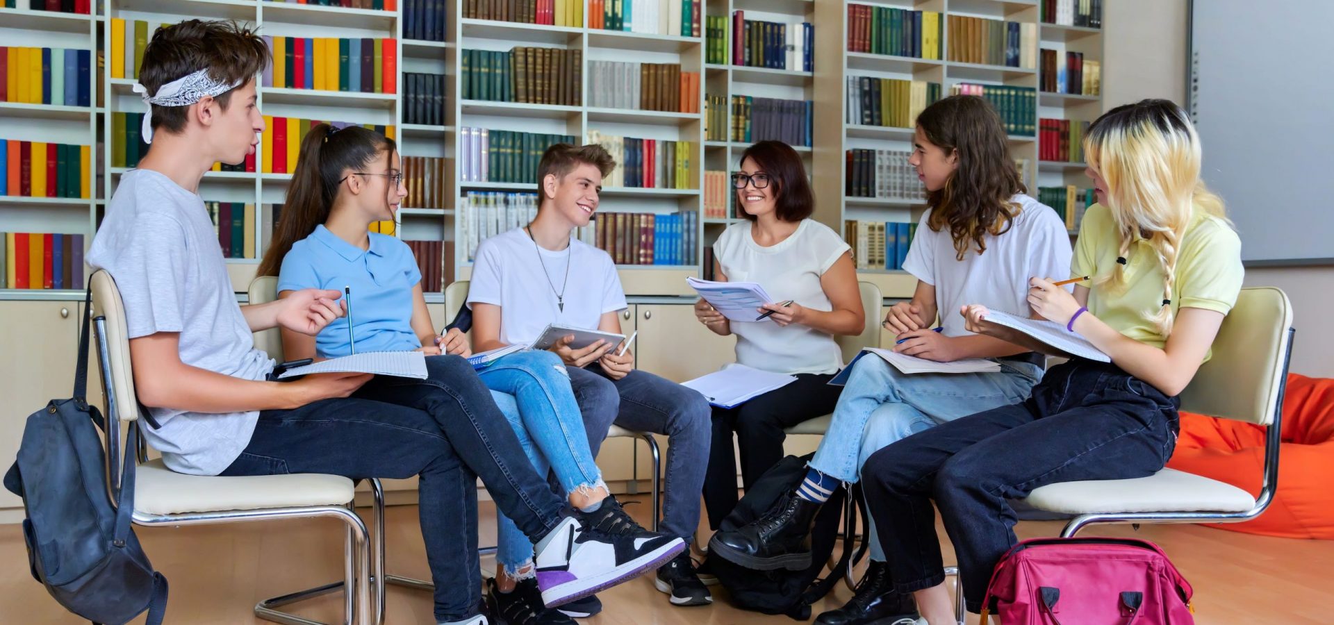 half circle of teacher with students in library setting
