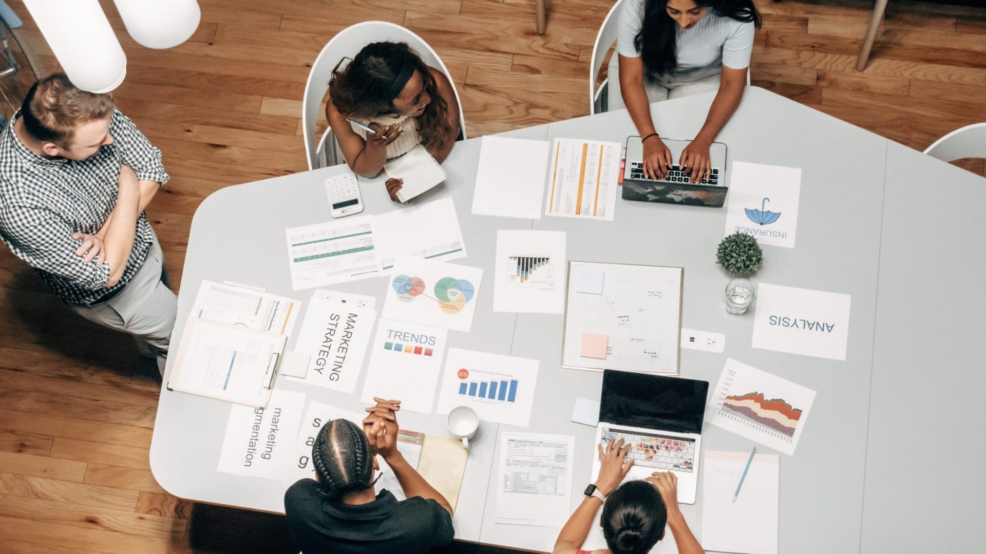 group of people with bunch of marketing documents on the table