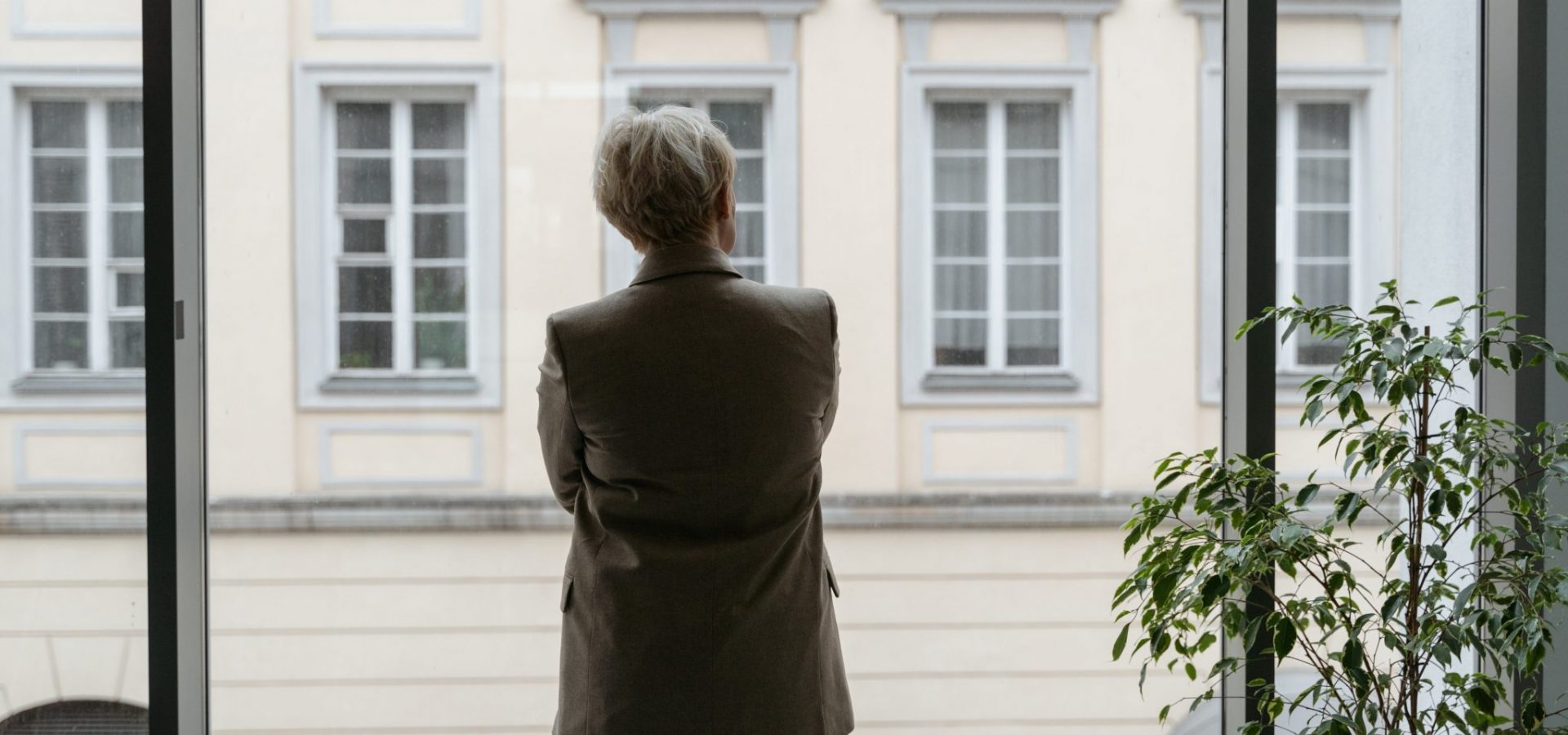 Woman in jacket looking out a window facing away from camera
