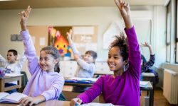 Classroom of students with their hands raised