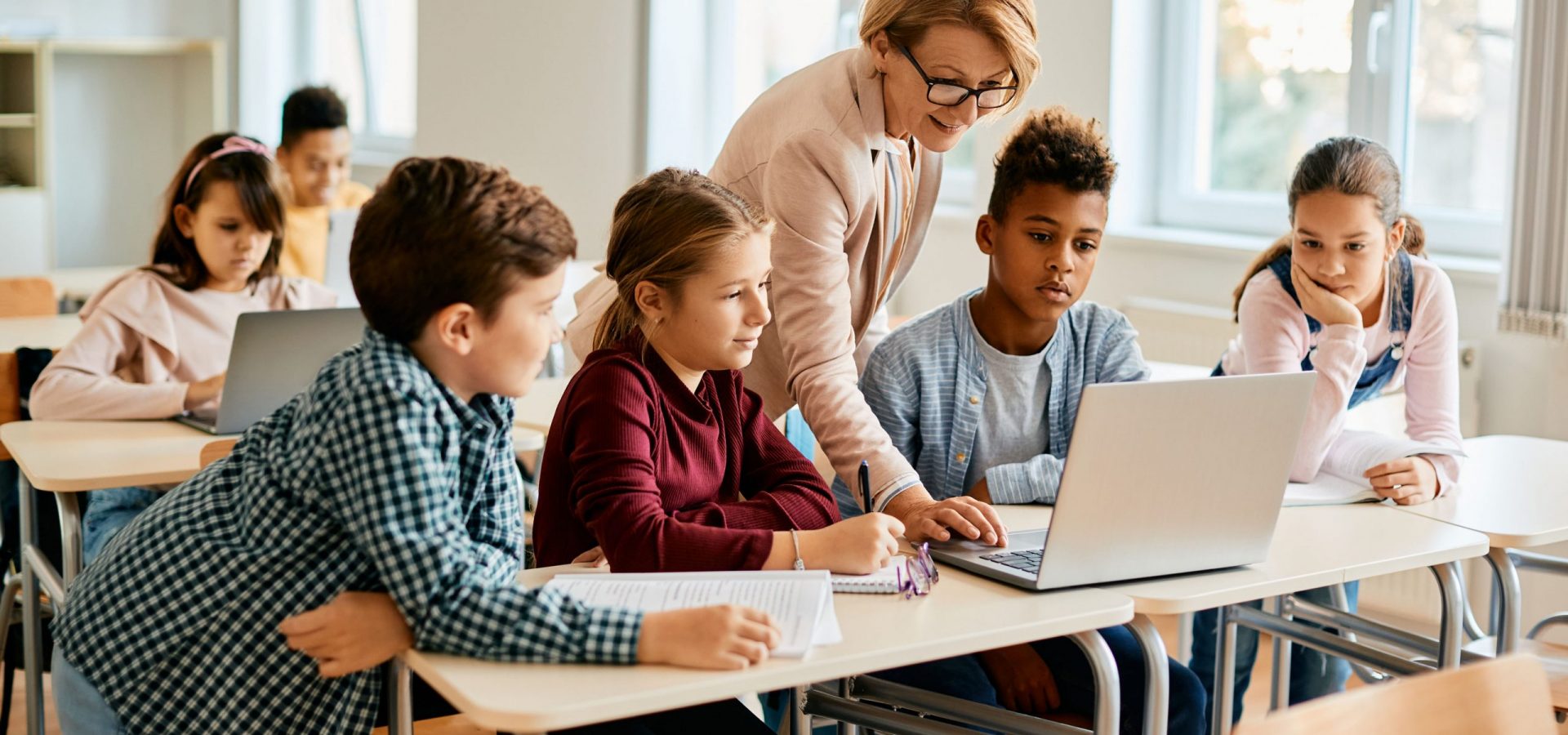 Group of elementary students having computer class with their teacher in the classroom.