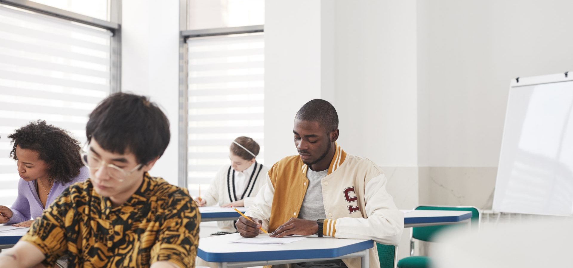 Students in classroom at their desk writing on paper