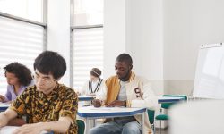 Students in classroom at their desk writing on paper