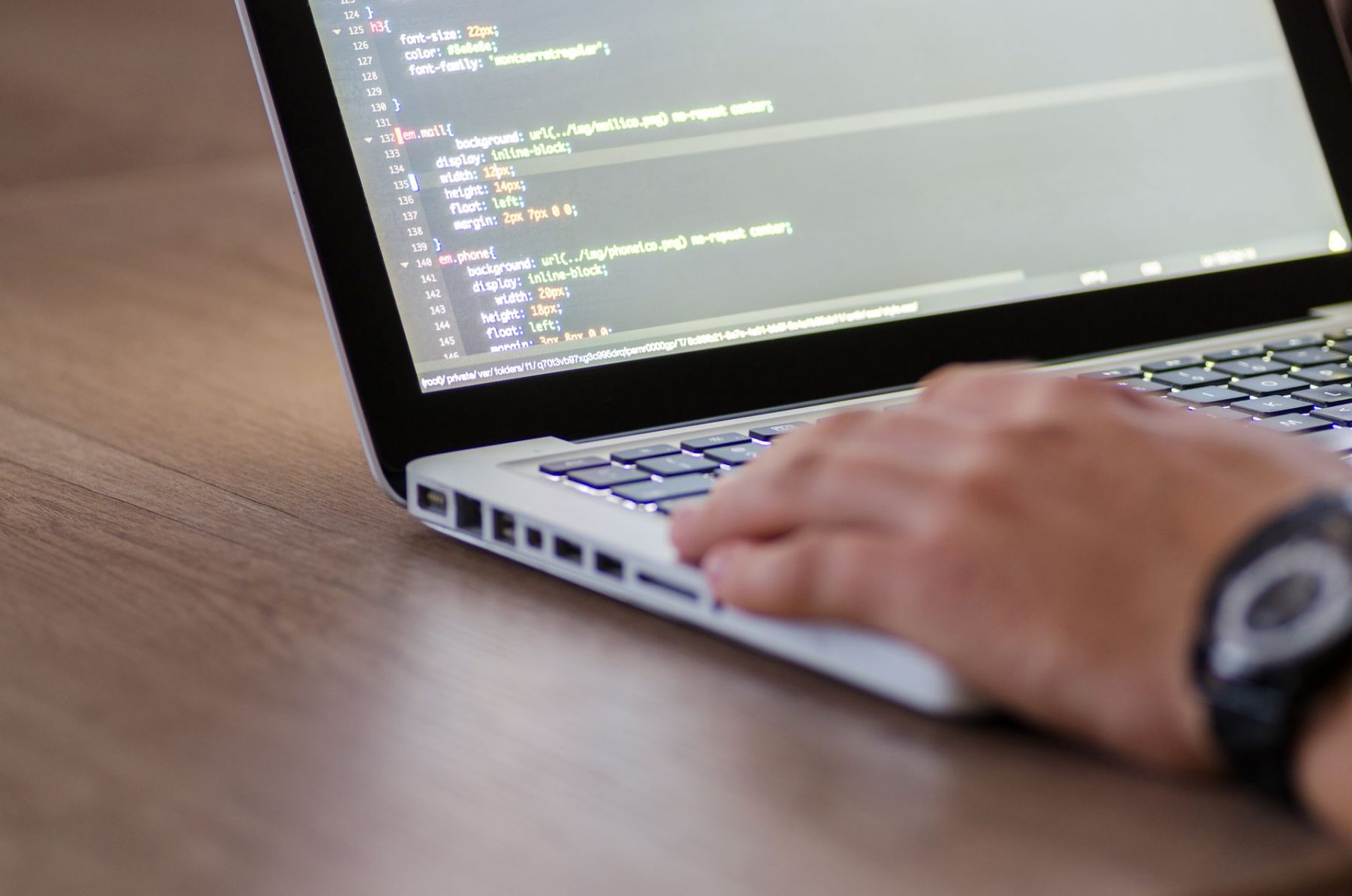 Person typing on laptop with string of codes showing on screen