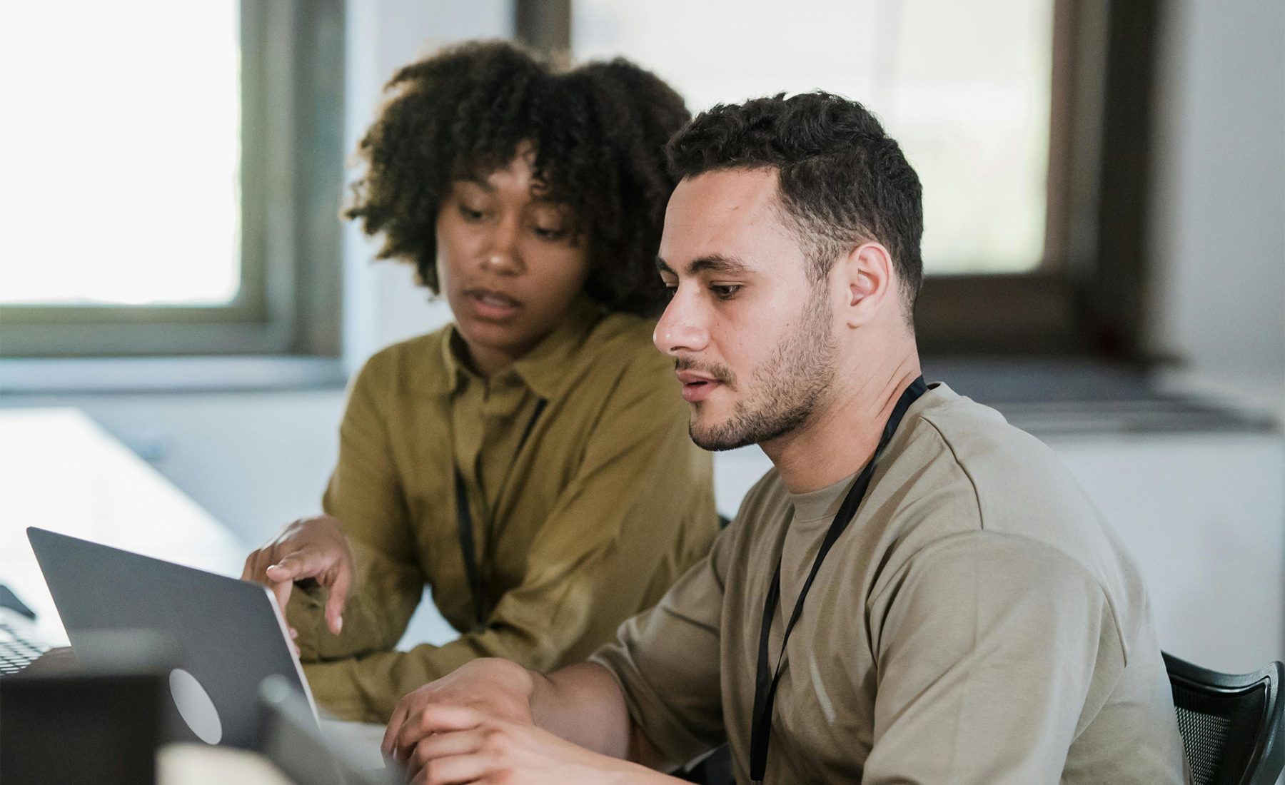 man and woman sitting at a desk looking at a computer 